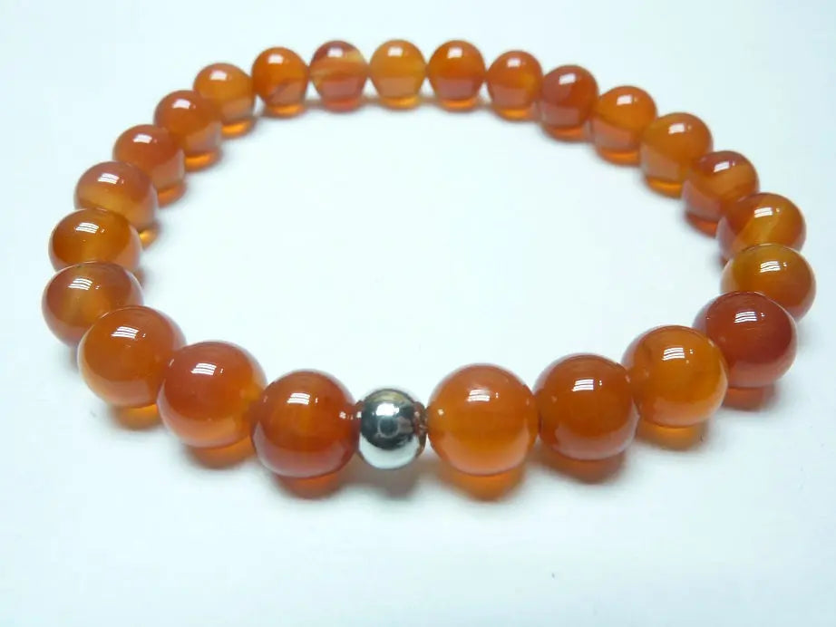 Bracelet en cornaline naturelle AAA, perles rondes orange translucide avec une perle centrale argentée, monté sur fil élastique.