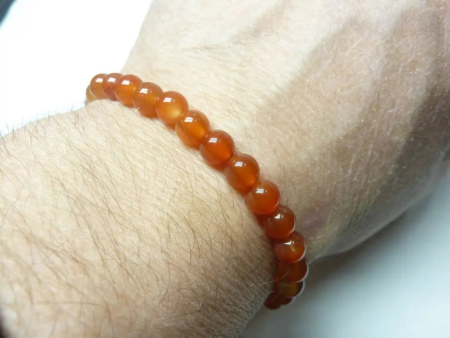 Bracelet en Cornaline naturel qualité AAA avec perles rondes monté sur fil élastique, porté au poignet.