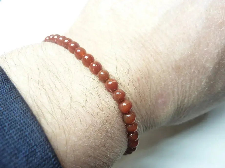 Bracelet réglable en perles de cornaline naturelle de qualité AAA porté au poignet, symbolisant énergie et vitalité.