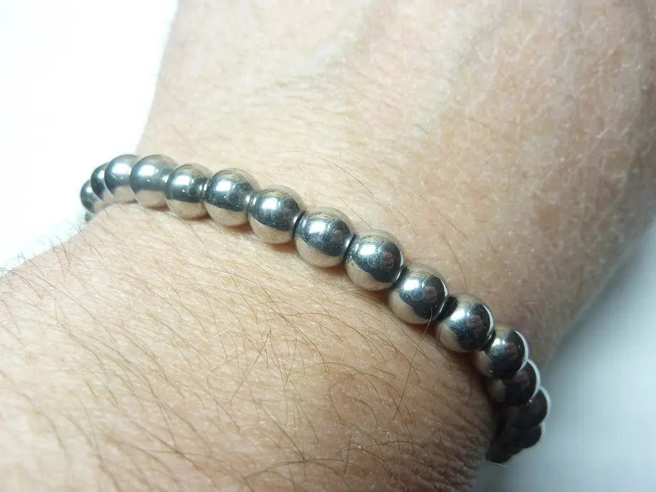 Bracelet en hématite naturelle AAA perles rondes monté sur fil élastique porté au poignet, bijou mixte de lithothérapie pour ancrage et protection.