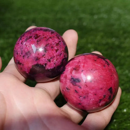 Sphère en Rhodonite rose polie avec veines noires tenue à la main, pierre de guérison émotionnelle et harmonie du cœur
