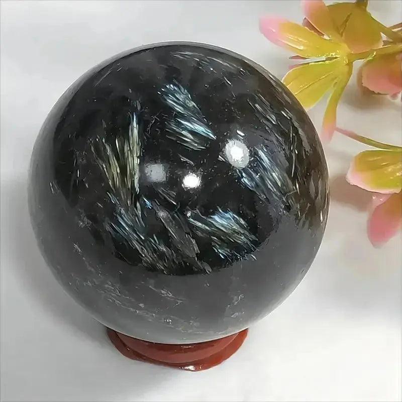 Sphère en Astrophyllite naturelle polie avec éclats métalliques bleutés, pierre de transformation et éclairage intérieur spirituel.